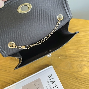 Fashionable black stone texture handbag with golden chain and clasp on a wooden table