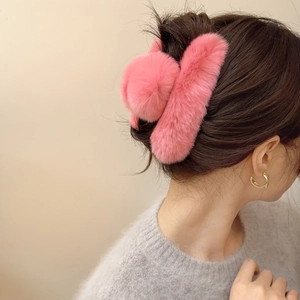 Detailed view of plush pink faux fur claw clip styled on back of head for winter