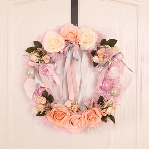 Pink artificial rose wreath with silk ribbons and feather wings on white door