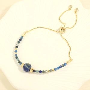 Detail of adjustable golden chain bracelet with blue sodalite beads on shell tray