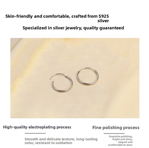 Macro shot of polished S925 sterling silver hoop earrings on soft silk fabric