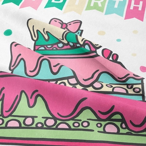 Close-up detail of cartoon birthday cake print and fabric texture on a white wall tapestry