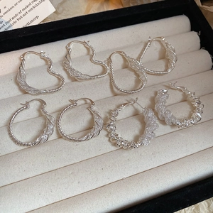 Detailed view of silver mesh and twisted rope hoop earrings on a velvet jewelry tray