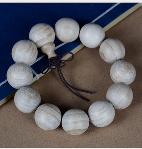 Detailed close-up of natural camphor wood prayer beads with delicate wood grain and knots