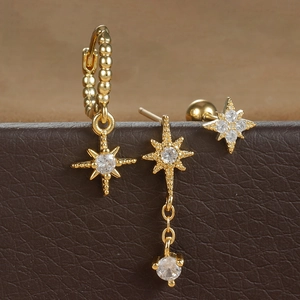 Macro shot of gold star tassel earrings set with cubic zirconia on brown leather