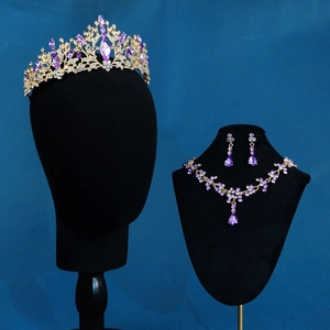 Detail of bridal jewelry set with purple crystals and gold crown on black mannequin
