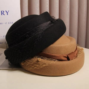 Detail of wool felt boater hats in black and camel with mesh veil and satin ribbon