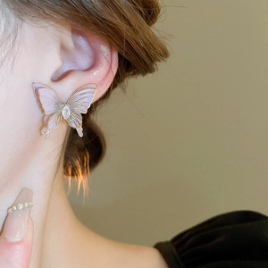 Detailed close-up of light purple butterfly stud earring with zircon on model's ear