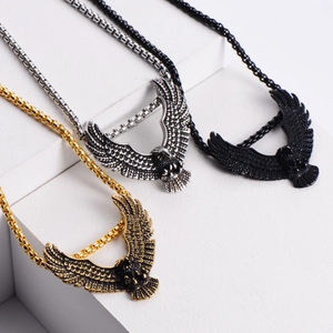 Detailed view of eagle pendant necklaces in gold, silver, and black on stone blocks