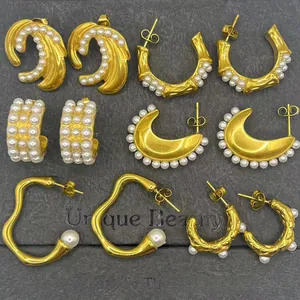 Flat lay of vintage 18k gold pearl earrings in hoop, crescent, and wavy designs