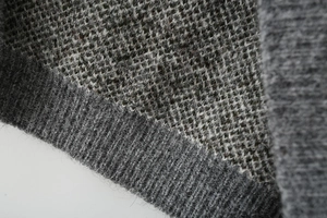 Detailed macro view of gray mélange knit fabric with ribbed cuff finish and soft texture
