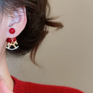 Détail de boucles d'oreilles perles rouges avec cheval à bascule doré et cristaux