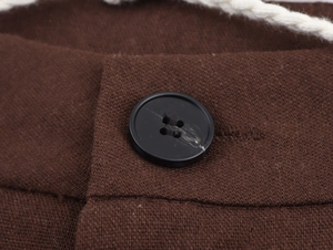 Detail of dark brown ethnic trousers featuring a black button and white braided drawstring