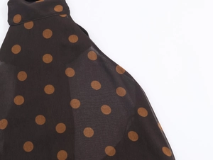 Close-up of black chiffon fabric with brown polka dots showing detailed texture and seams