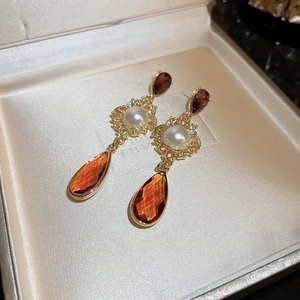 Close-up of vintage floral drop earrings with gold carving and amber gemstones