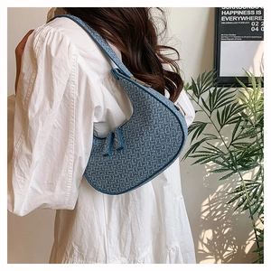 Blue woven crescent hobo bag with grid texture shown on a white shirt dress