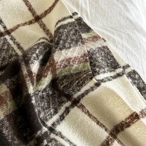 Close-up of soft plaid scarf fabric showing brown and green checkered wool texture