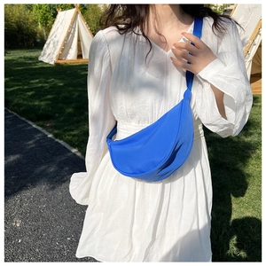 Blue nylon crescent bag shown in an outdoor camping scene with a white summer dress