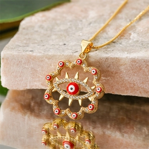 Macro détaillée d'un collier Evil Eye doré avec émail rouge et strass blancs scintillants