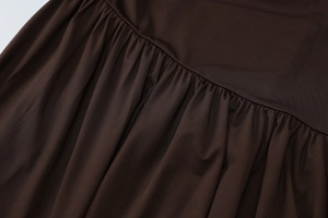 Detail shot of deep brown pleated fabric with soft texture and elegant draped waistline