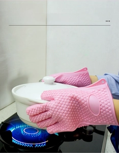 Pink heat resistant silicone kitchen oven mitts with non-slip texture on white ceramic pot