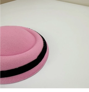 Detail of bright pink wool felt hat featuring black velvet ribbon trim and texture