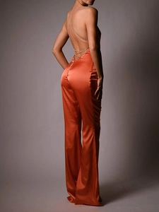 Detail of orange satin jumpsuit with a crisscross thin chain open back design