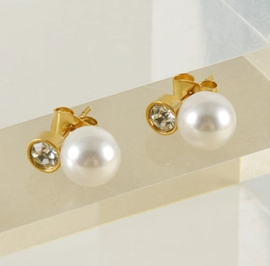 Dettaglio di orecchini in acciaio placcato oro 18k con perla bianca e zircone lucido