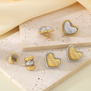 Macro detail of 18K gold-plated heart earrings with wavy texture on stone display
