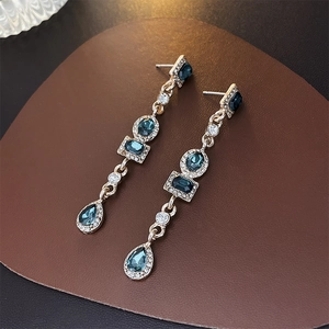 Gros plan détaillé de boucles d'oreilles vintage en or avec pierres émeraude et bleues