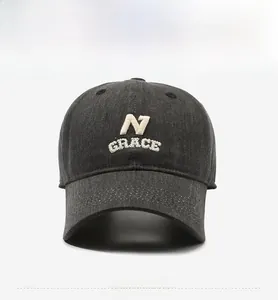 Detail of 3D embroidered N GRACE lettering on charcoal grey washed denim baseball cap