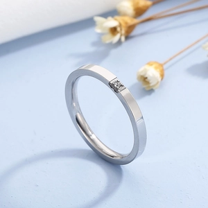 Détail macro d'une bague en acier titane argenté avec diamant sur fond bleu doux