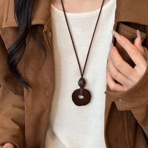 Retro brown resin pendant necklace with dark cord on model wearing a sweater