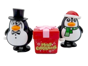 Close-up of wind-up Christmas penguin and gift box toys with Merry Christmas text