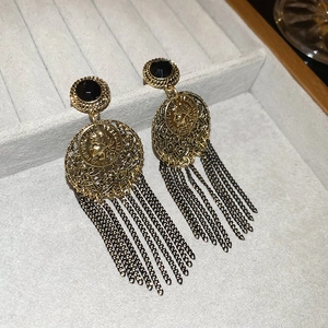Macro detail of vintage gold earrings featuring coin relief and long chain tassels