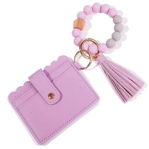 Close-up of purple PU leather card holder with silicone bead bracelet and tassel keychain