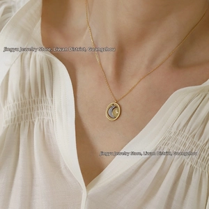 Detail of two-tone moon and star oval pendant on a gold titanium steel necklace