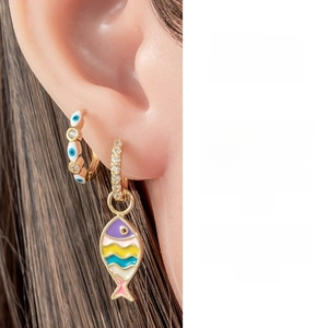 Detail of bohemian gold hoop earrings featuring enamel evil eye and colorful fish charm