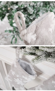 Détail d'une chaussette de Noël en peluche grise avec motifs de flocons de neige blancs