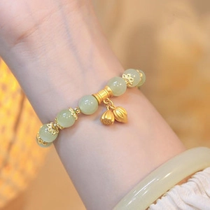 Detail of light green aventurine bead bracelet with golden lotus pendant on model wrist