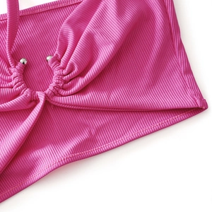 Détail d'un crop top rose en maille côtelée avec fronces et perle métallique centrale