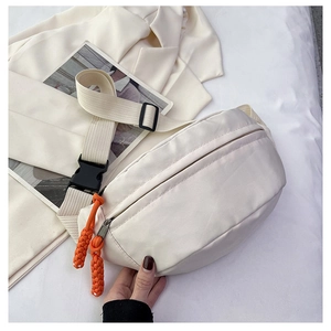 Detail of canvas chest bag with bright orange woven zipper pulls and black buckle