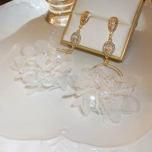 Detailed macro of crystal flower earrings with ivory petals on a vintage jewelry plate