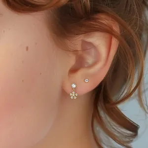 Close-up of elegant s925 silver golden flower earrings with zircon on woman's ear