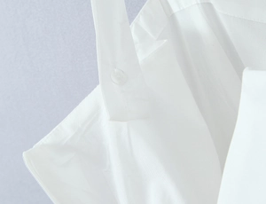 Close-up of shoulder strap button and fabric texture on a white square neck dress