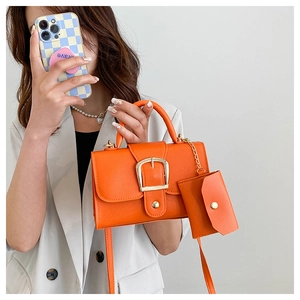 Detail of orange lychee leather handbag with gold buckle and mini pouch accessory