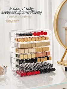 Clear acrylic tiered lipstick organizer rack showing multiple rows on a vanity