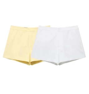 Detailed flat lay of women's minimalist shorts in pale yellow and crisp white woven fabric