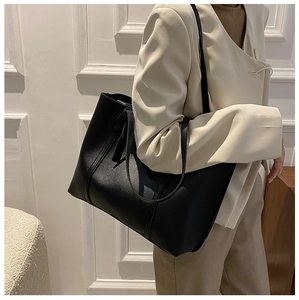 Modern black oversized leather tote bag styled with a beige blazer for office wear