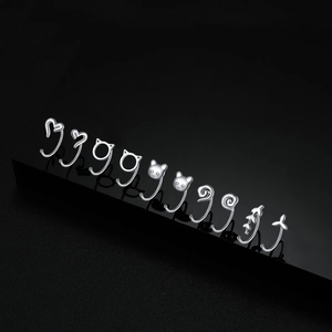 Minimalist S999 silver cat and heart-shaped hoop earring set on black reflective surface